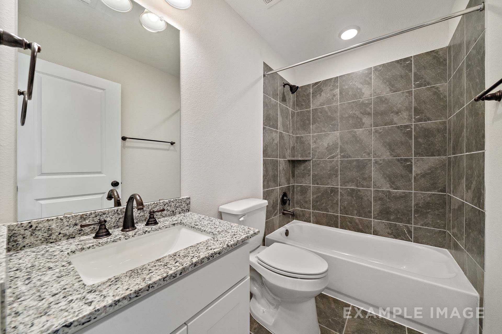 Spacious master bathroom in The Victoria A featuring double granite vanity, tiled walk-in shower, soaking tub, and modern fixtures