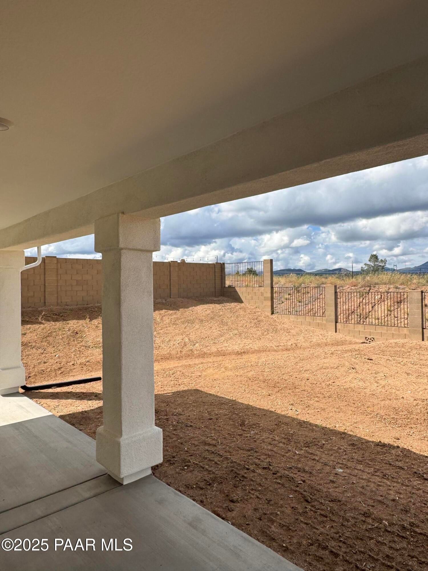 Covered back patio with stucco pillars overlooking desert backyard and mountains in Westwood, Prescott, Arizona