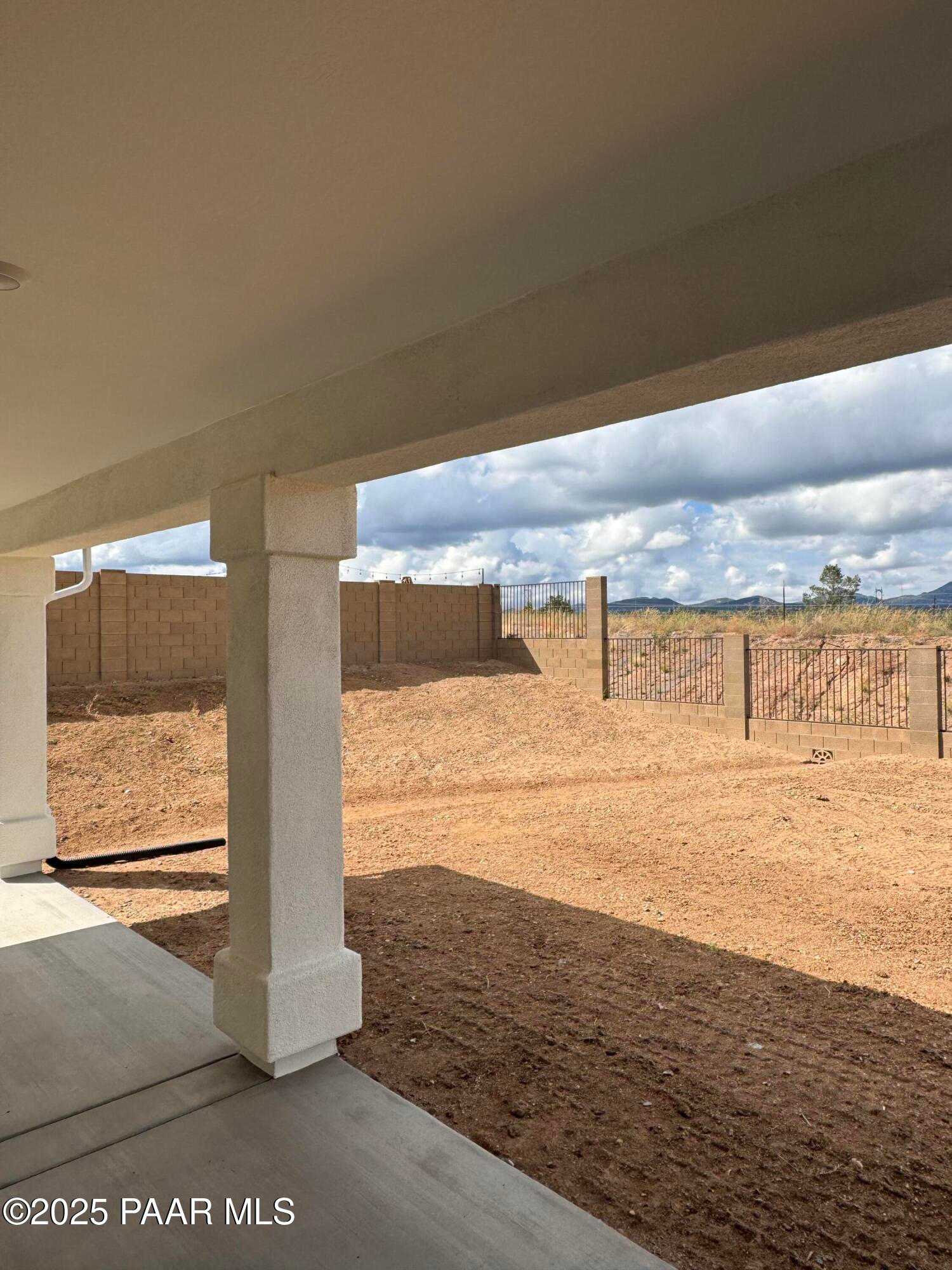 Covered back patio with stucco pillars overlooking desert backyard and mountains in Westwood, Prescott, Arizona