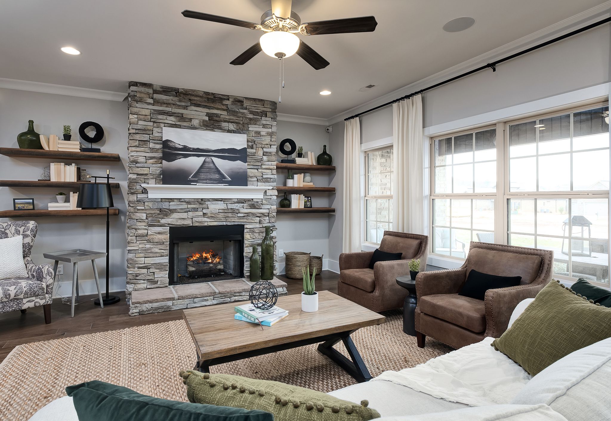 Cozy living room in Chimney Creek home Hampton Cove Alabama with stone fireplace built-in shelves and armchairs