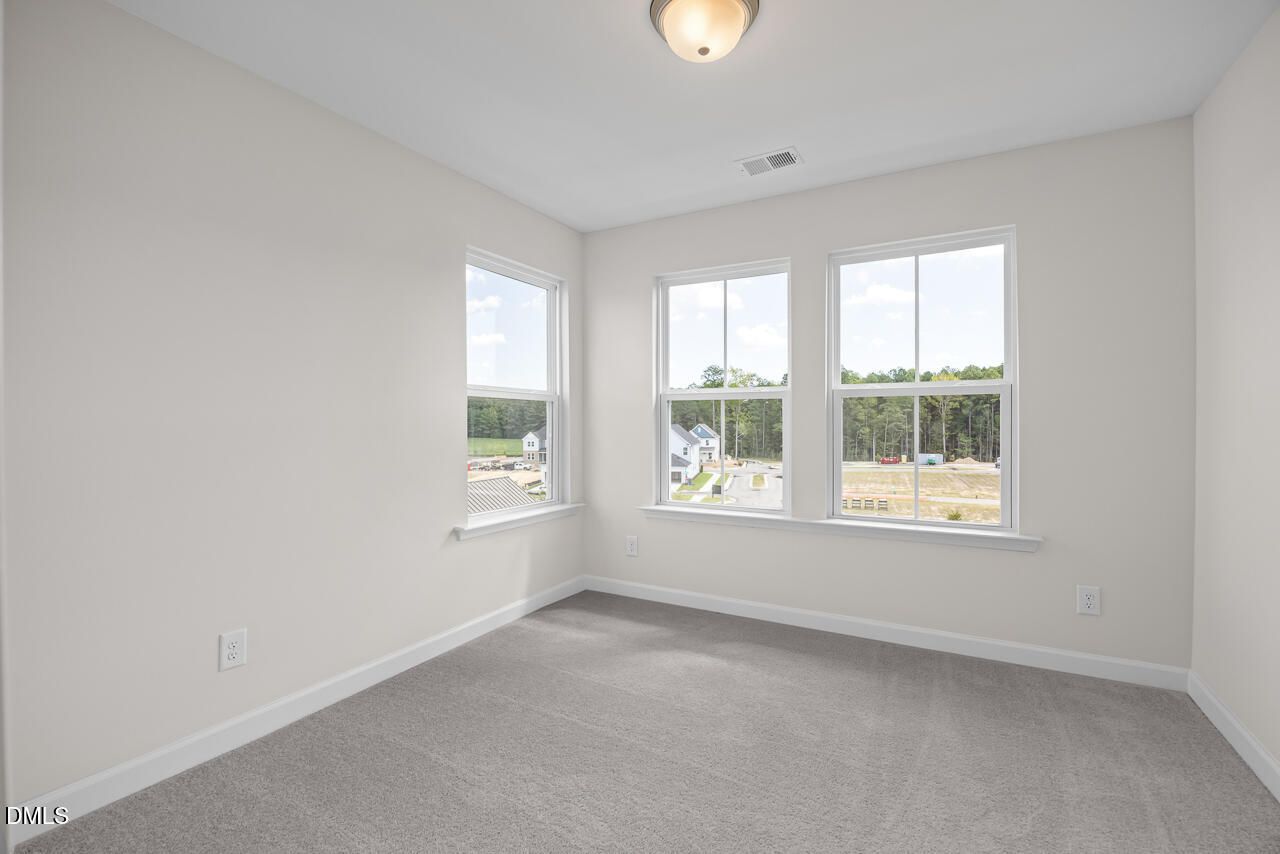 Bright bedroom with neutral walls, carpet flooring, and multiple windows at Forestville Yard Townhomes, Knightdale, NC by Davidson Homes