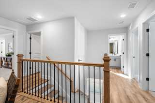 Upstairs hallway in The Washington H townhome by Davidson Homes, Marietta GA, with oak wood railing, stairs, and adjacent bedroom doors