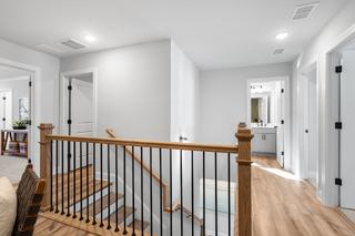 Upstairs hallway in The Washington H townhome by Davidson Homes, Marietta GA, with oak wood railing, stairs, and adjacent bedroom doors