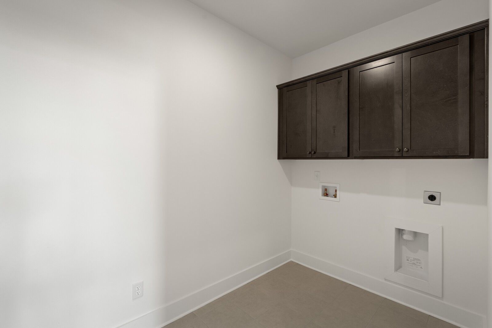 Laundry room with dark wood cabinets and tile flooring in The Ridgeport C floor plan at Woods Crossing, Gallatin, TN.