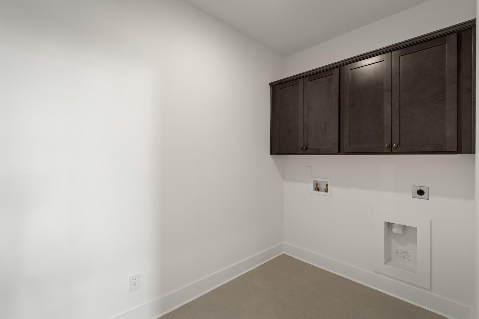 Laundry room with dark wood cabinets and tile flooring in The Ridgeport C floor plan at Woods Crossing, Gallatin, TN.