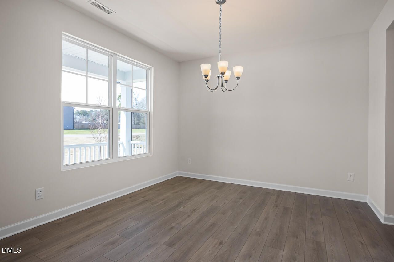 Bright dining room with four-light chandelier, hardwood floors, and large windows in Davidson Homes The Ash B, Lillington, NC