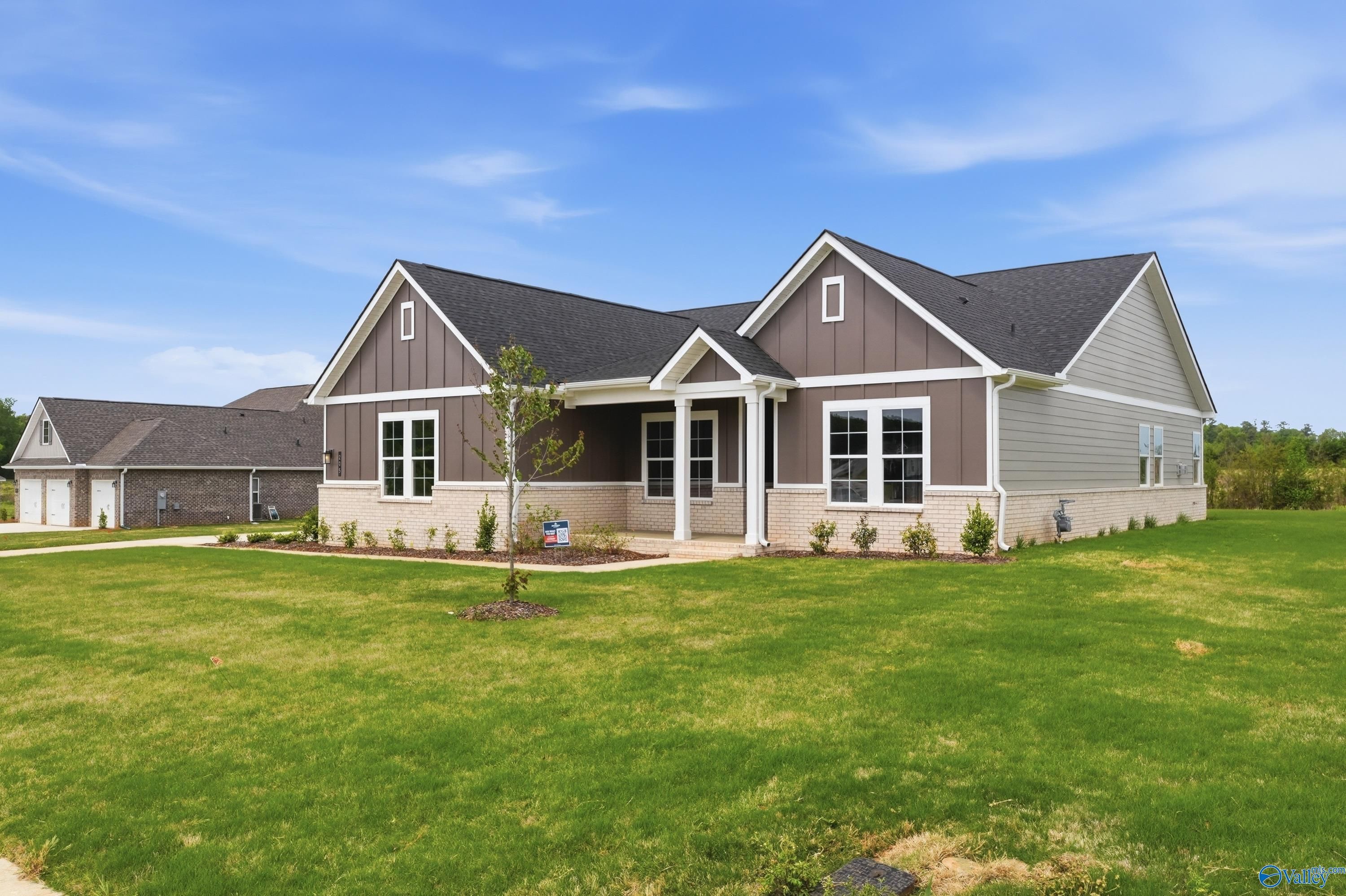 Modern single-story home with gray siding, covered porch, large windows, and lush green yard in Riverton Preserve, Huntsville, Alabama