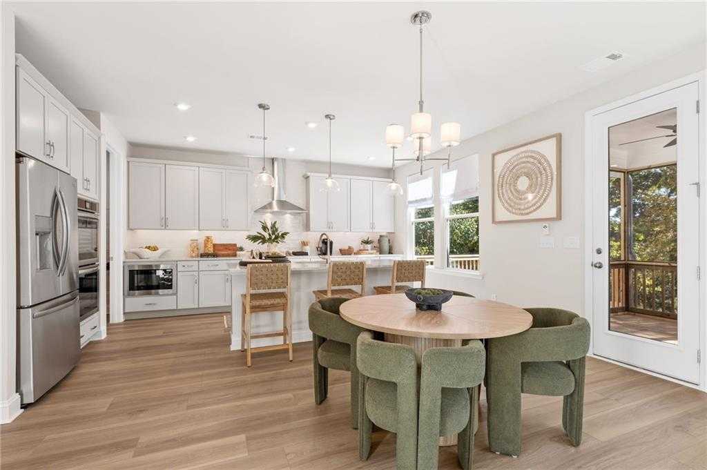 Modern open-concept kitchen with white cabinets, stainless appliances, island, and round dining table in The Danbury C, Buford, Georgia