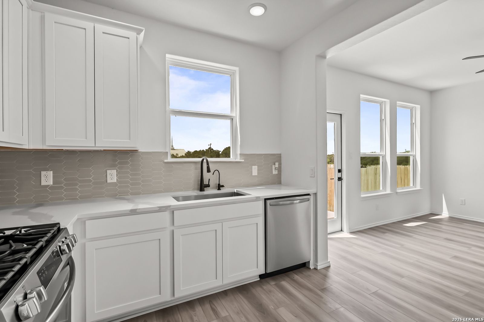 Modern kitchen with white cabinets, stainless appliances, and sink in The Florence B home at Meadows at Oak Creek, SA.