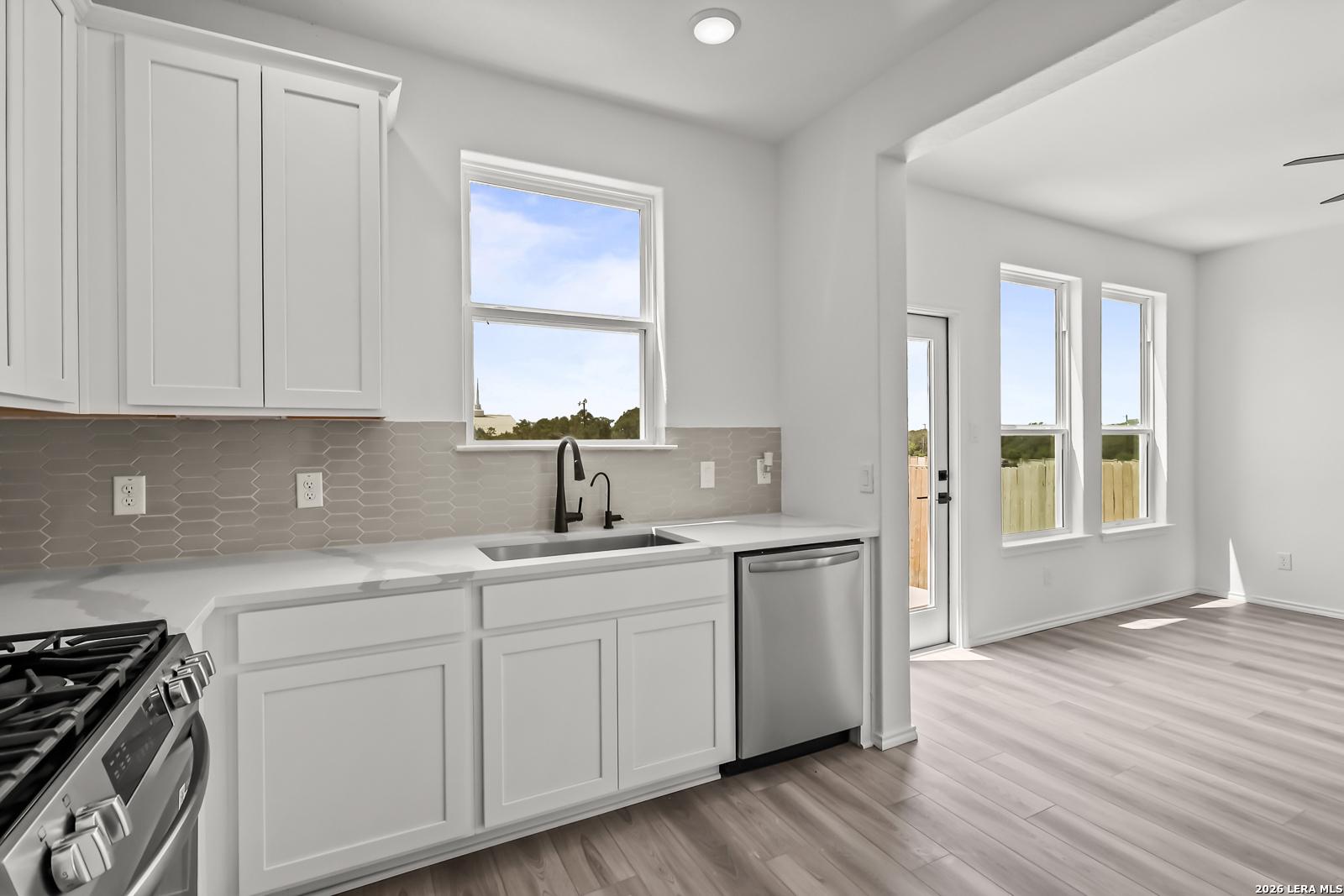 Modern kitchen with white cabinets, stainless appliances, and sink in The Florence B home at Meadows at Oak Creek, SA.