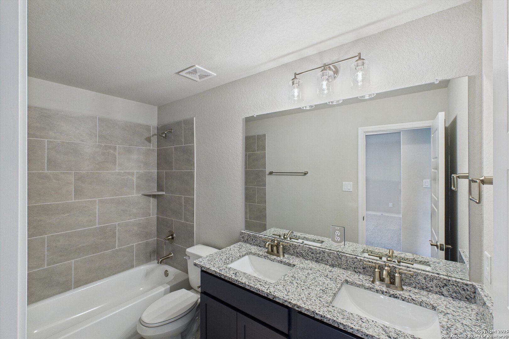 Spacious master bathroom featuring double granite vanity, soaking tub, tiled shower and modern fixtures in The Jennings H, Ladera, San Antonio