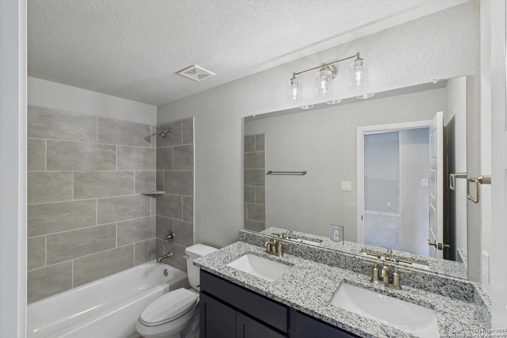 Spacious master bathroom featuring double granite vanity, soaking tub, tiled shower and modern fixtures in The Jennings H, Ladera, San Antonio