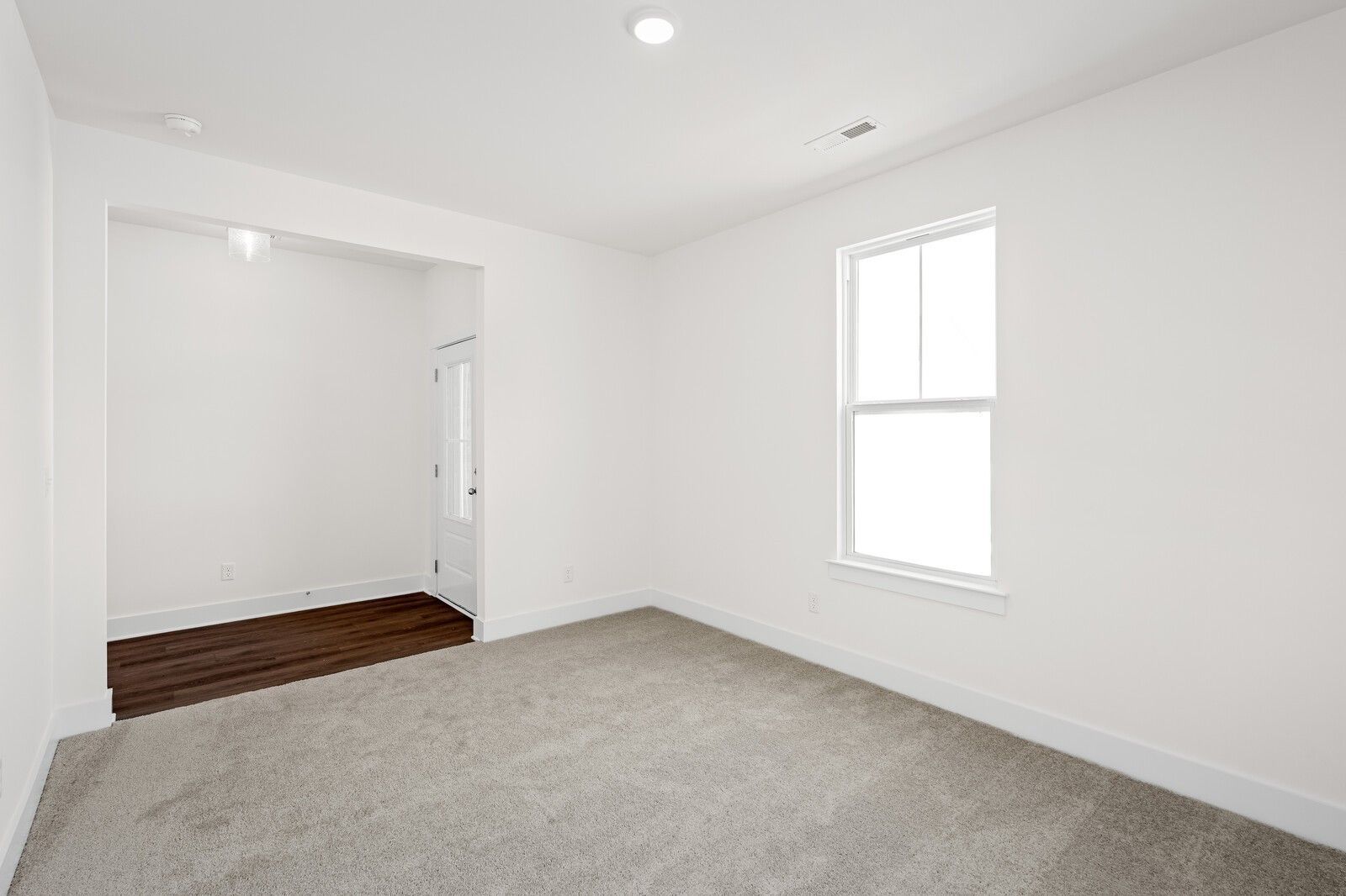 Bright carpeted bedroom with large window and wood-look flooring in Davidson Homes' Cottonwood E plan, Gallatin, Tennessee