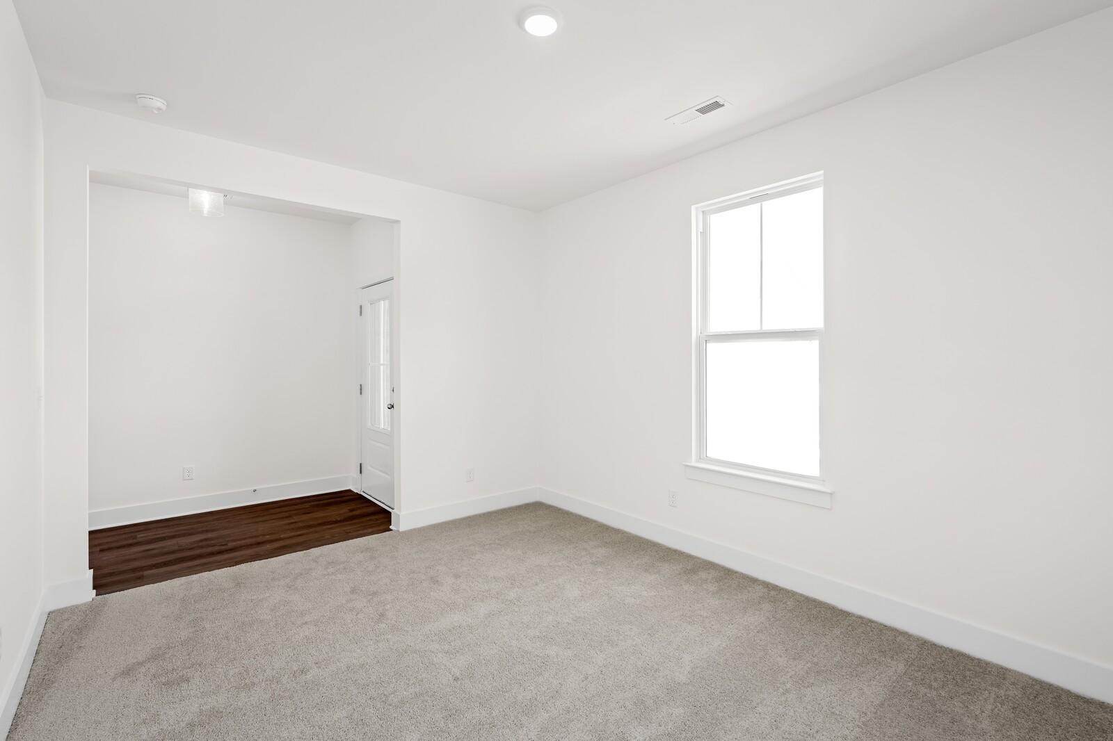 Bright carpeted bedroom with large window and wood-look flooring in Davidson Homes' Cottonwood E plan, Gallatin, Tennessee