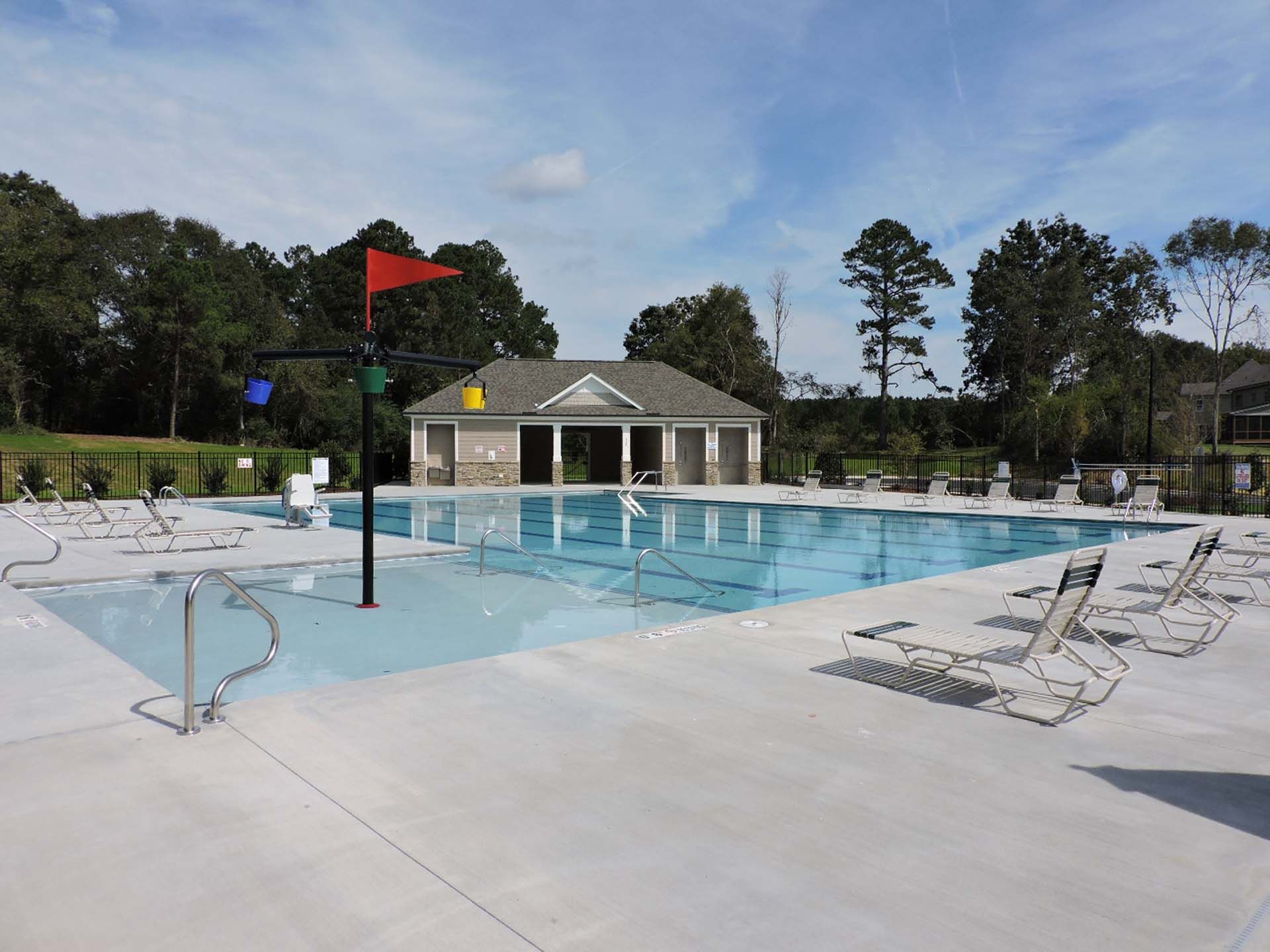 Resort-style swimming pool at Camden Park in Knightdale NC with lounge chairs, umbrellas and shaded pool house