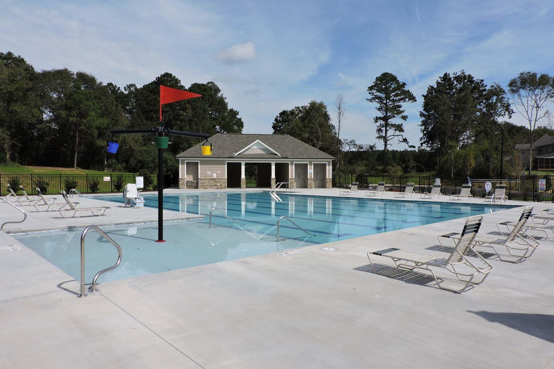 Resort-style swimming pool at Camden Park in Knightdale NC with lounge chairs, umbrellas and shaded pool house