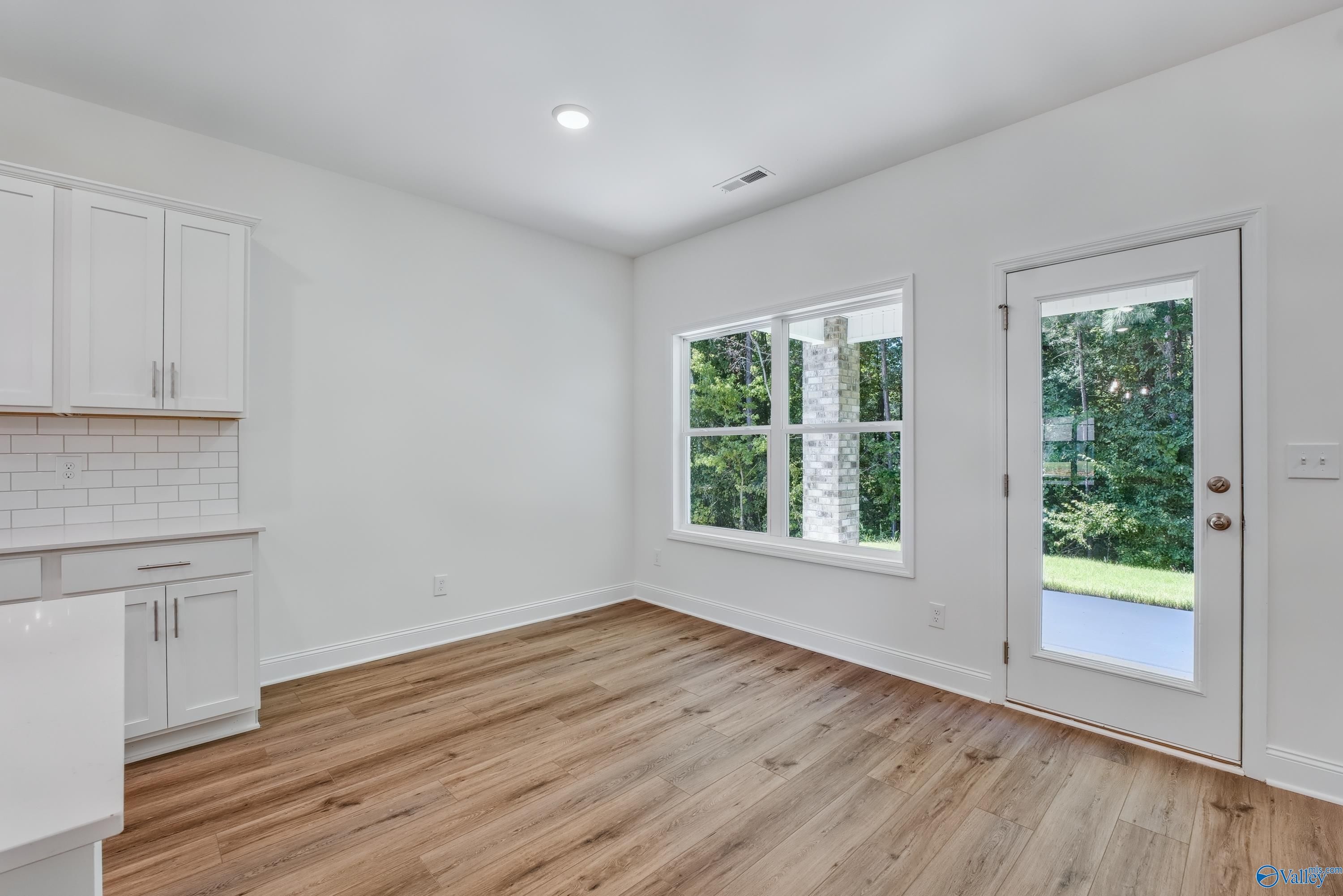 Bright kitchen featuring white shaker cabinets, subway tile backsplash, farmhouse sink, and large windows to wooded view in Davidson Homes Shelby A, Arab, Alabama
