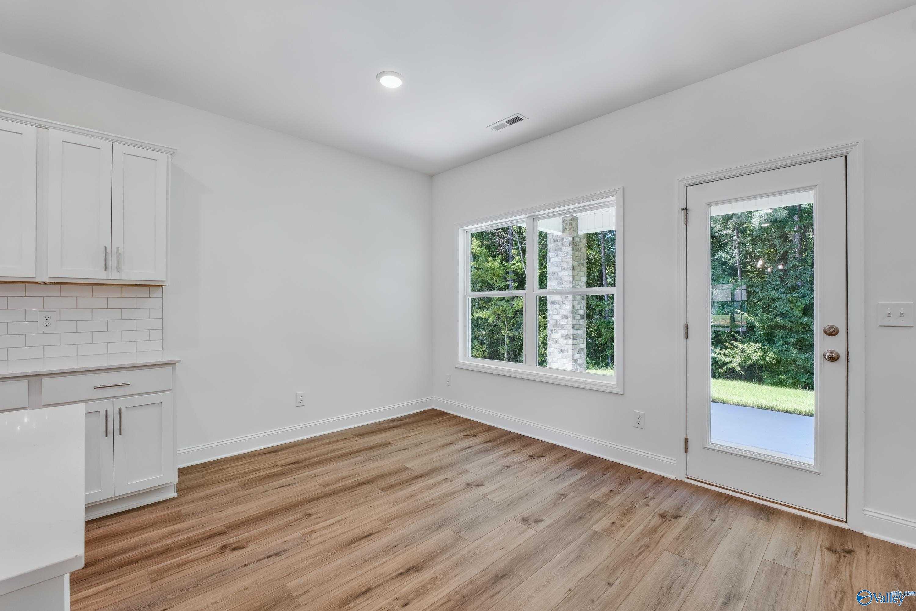 Bright kitchen featuring white shaker cabinets, subway tile backsplash, farmhouse sink, and large windows to wooded view in Davidson Homes Shelby A, Arab, Alabama