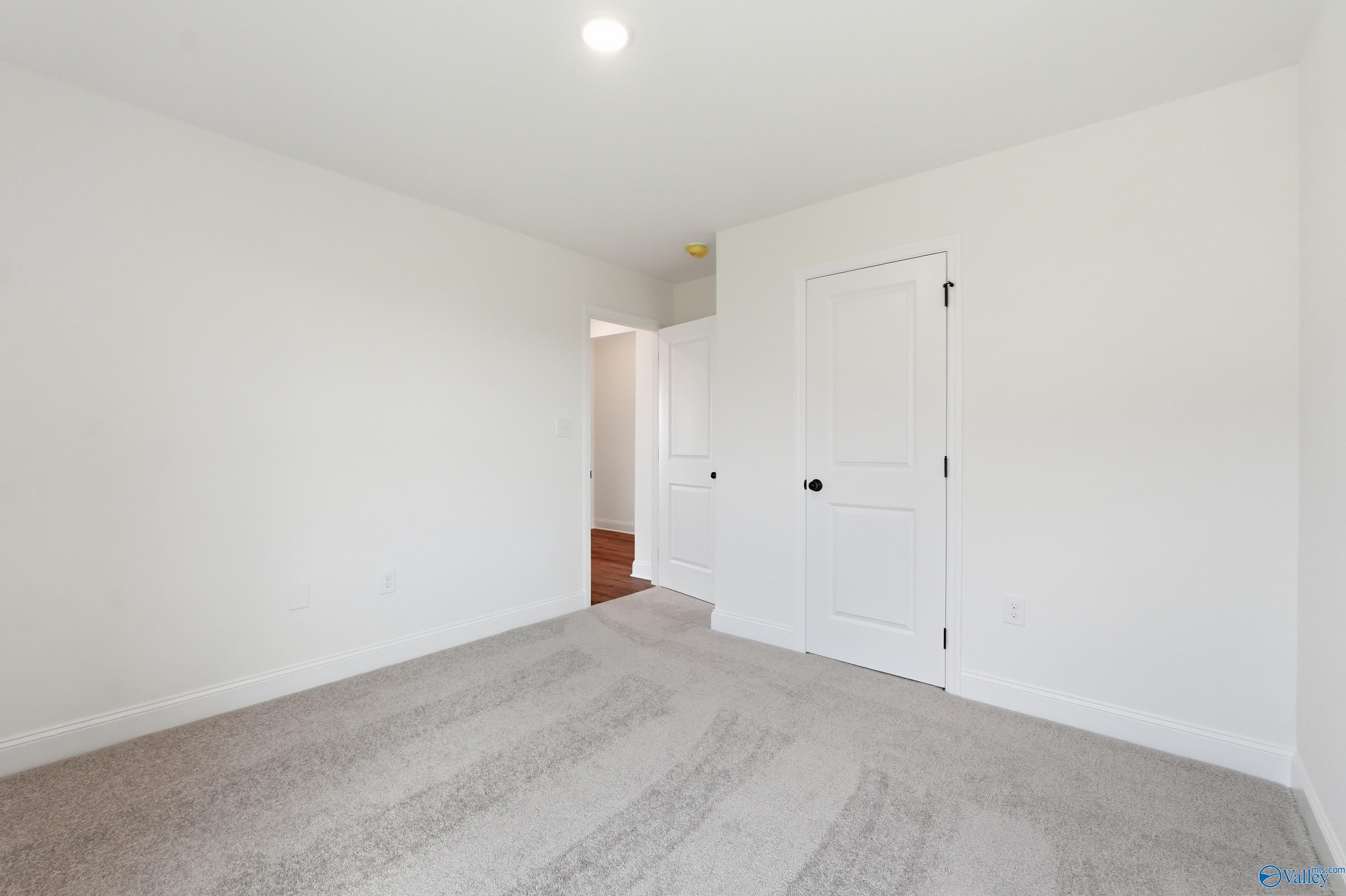 Bright carpeted bedroom with white interior doors in The Franklin floor plan by Davidson Homes in New Market, AL.