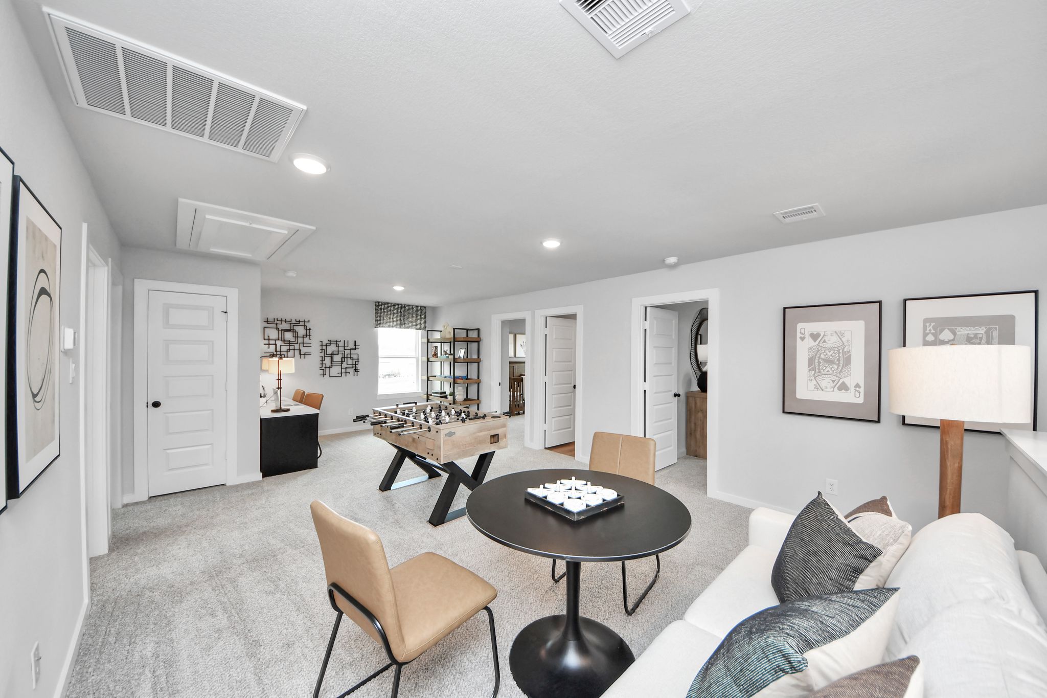 Spacious game room at Robins Landing in Houston with foosball table, lounge seating, and modern decor by Davidson Homes.