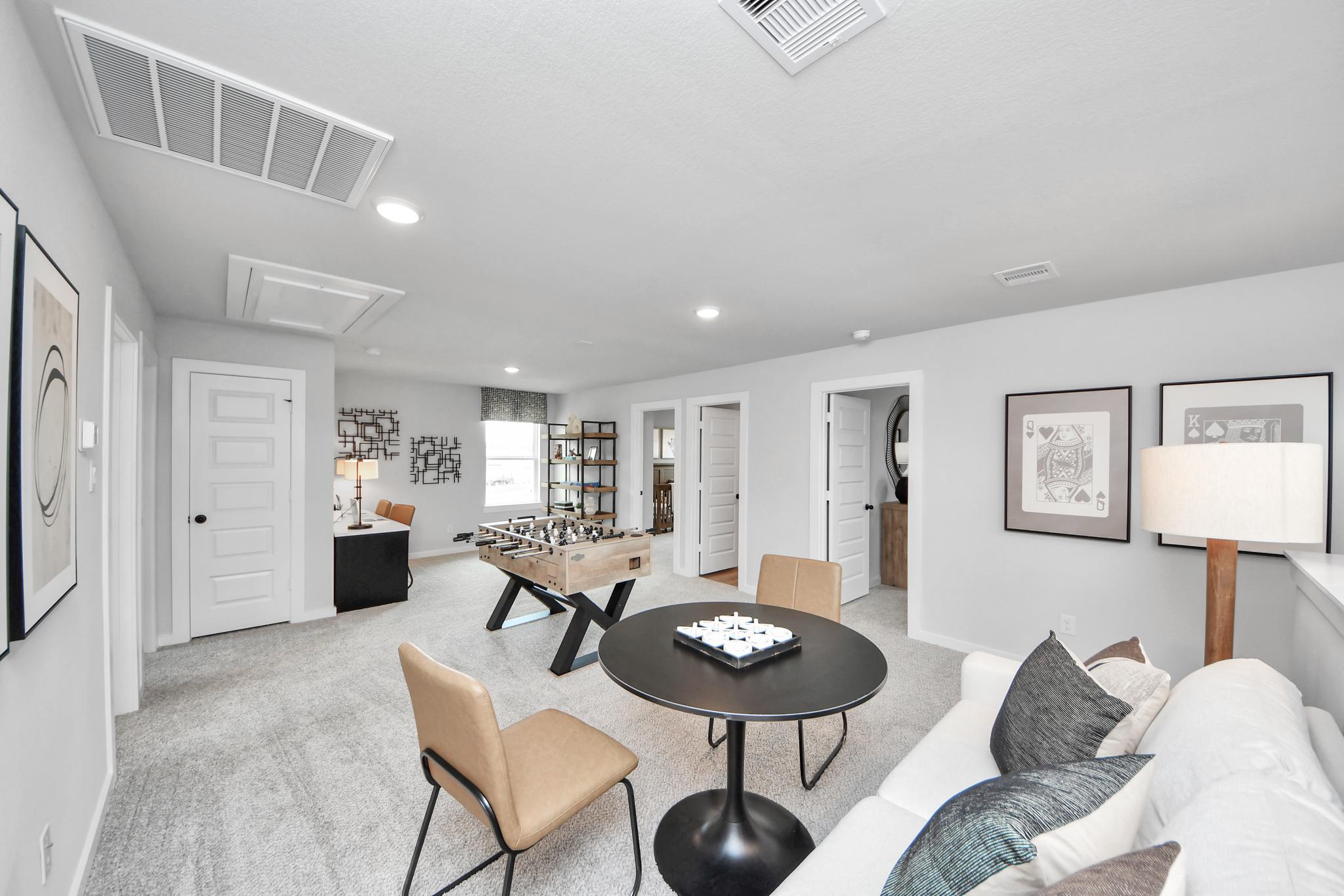 Spacious game room at Robins Landing in Houston with foosball table, lounge seating, and modern decor by Davidson Homes.