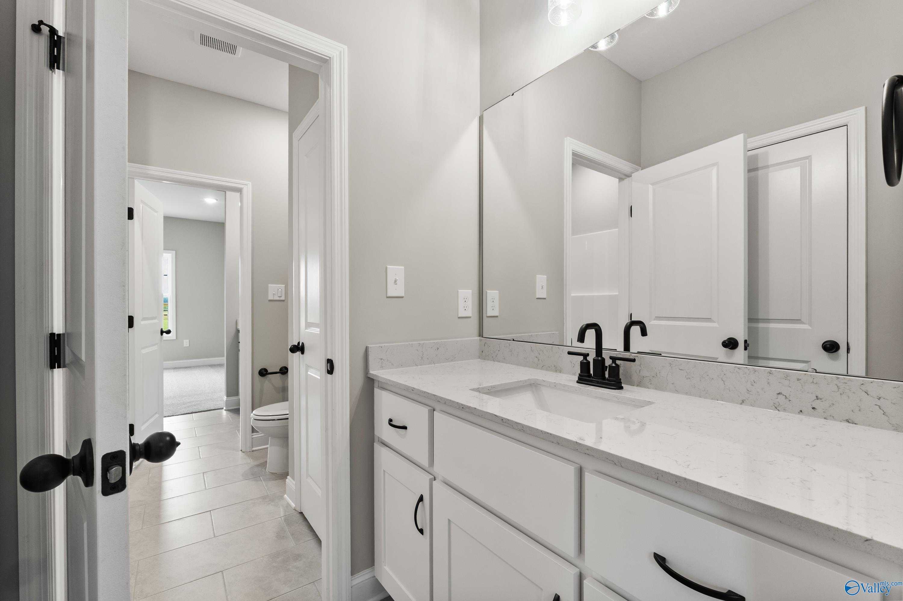 Modern primary bathroom with white shaker vanity, quartz countertop, black faucet in Davidson Homes The Finleigh, Toney AL
