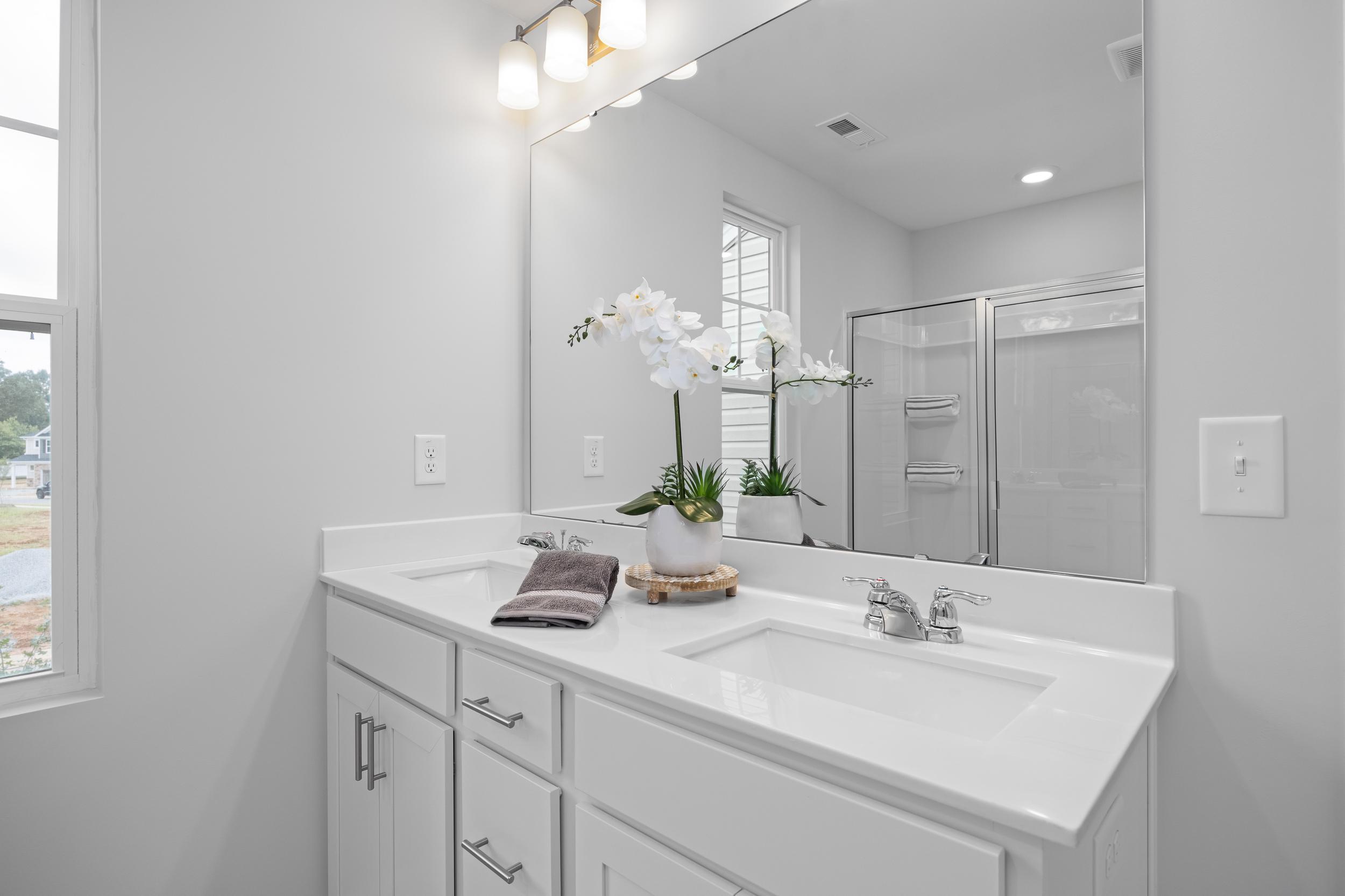 Modern master bathroom with dual-sink vanity and large mirror in The Warren home design by Davidson Homes.