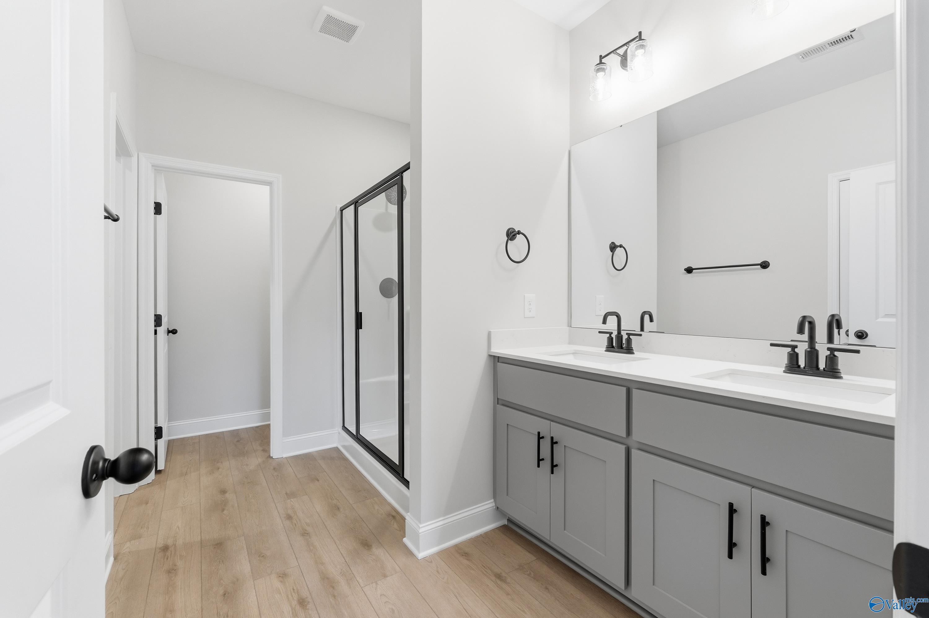 Modern master bathroom featuring double gray vanity, frameless glass shower, and luxury finishes in Davidson Homes The Daphne C, Athens, Alabama