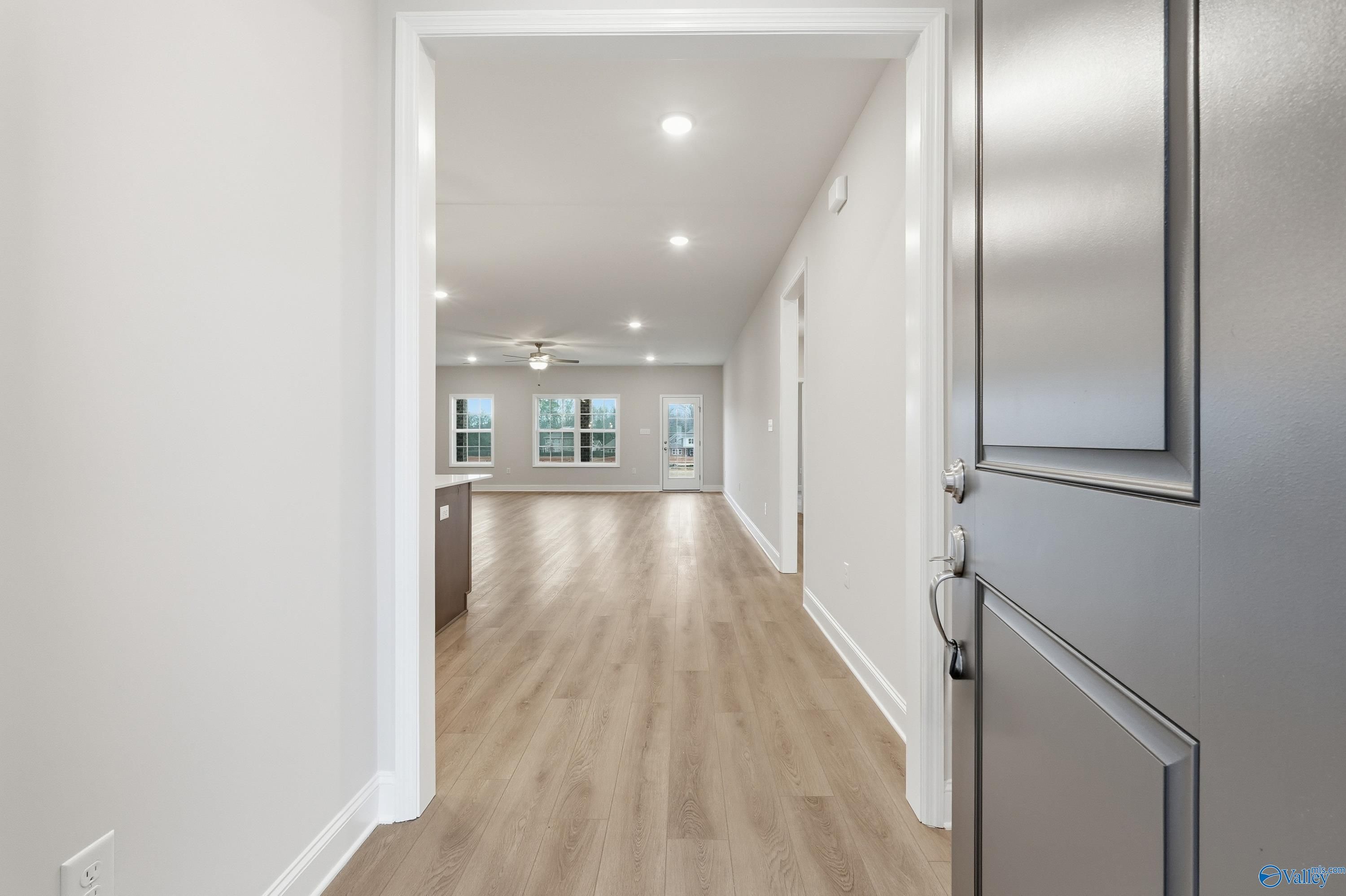 Open hallway with light hardwood floors, recessed lights, and ceiling fan leading to modern kitchen in Davidson Homes The Kirkland, Decatur AL