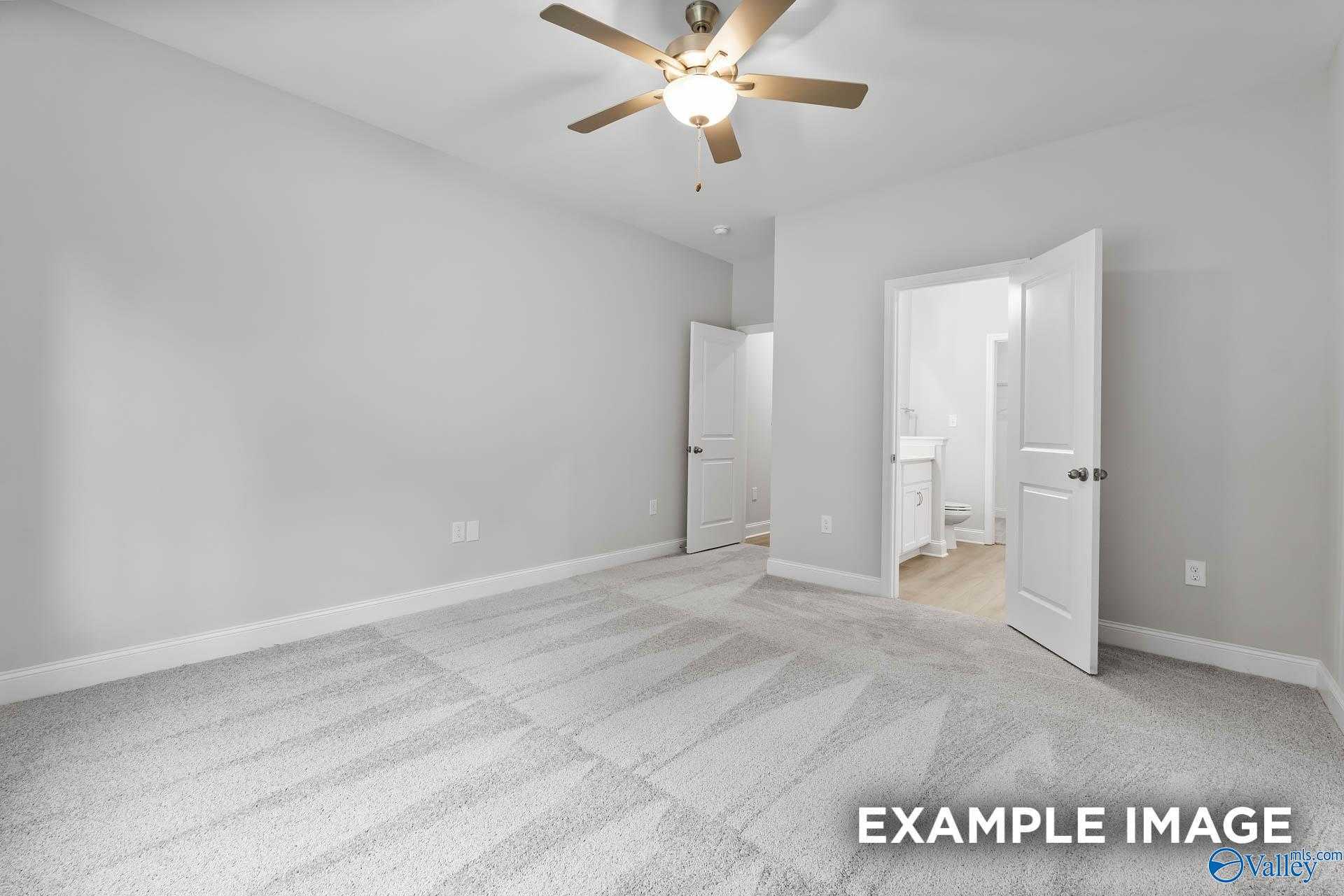 Spacious empty bedroom with ceiling fan, open bathroom door, and gray walls in Davidson Homes The Asheville C, Huntsville, Alabama