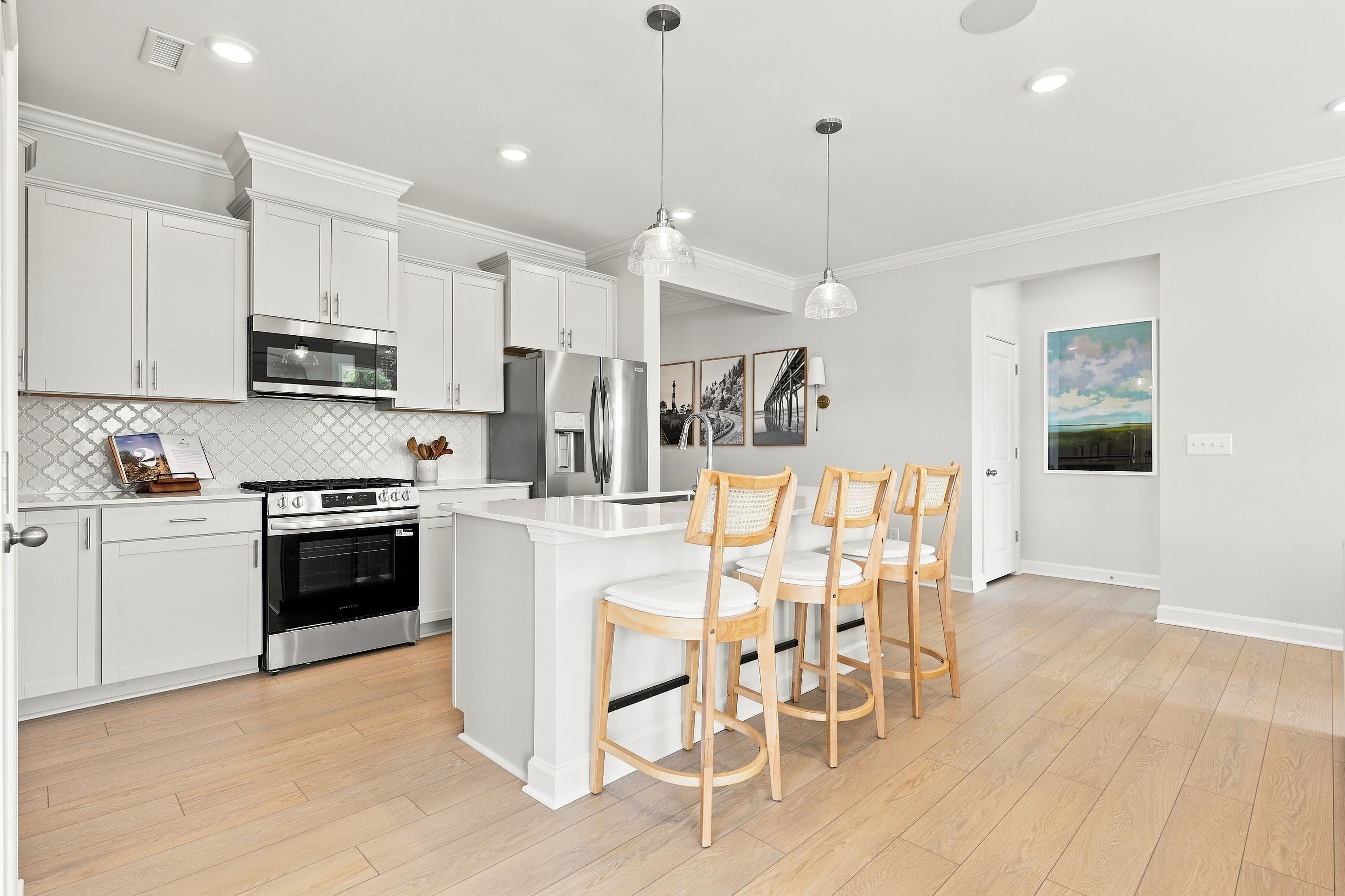Modern white kitchen in The Daphne D by Davidson Homes featuring a large island, stainless steel appliances, and seating.
