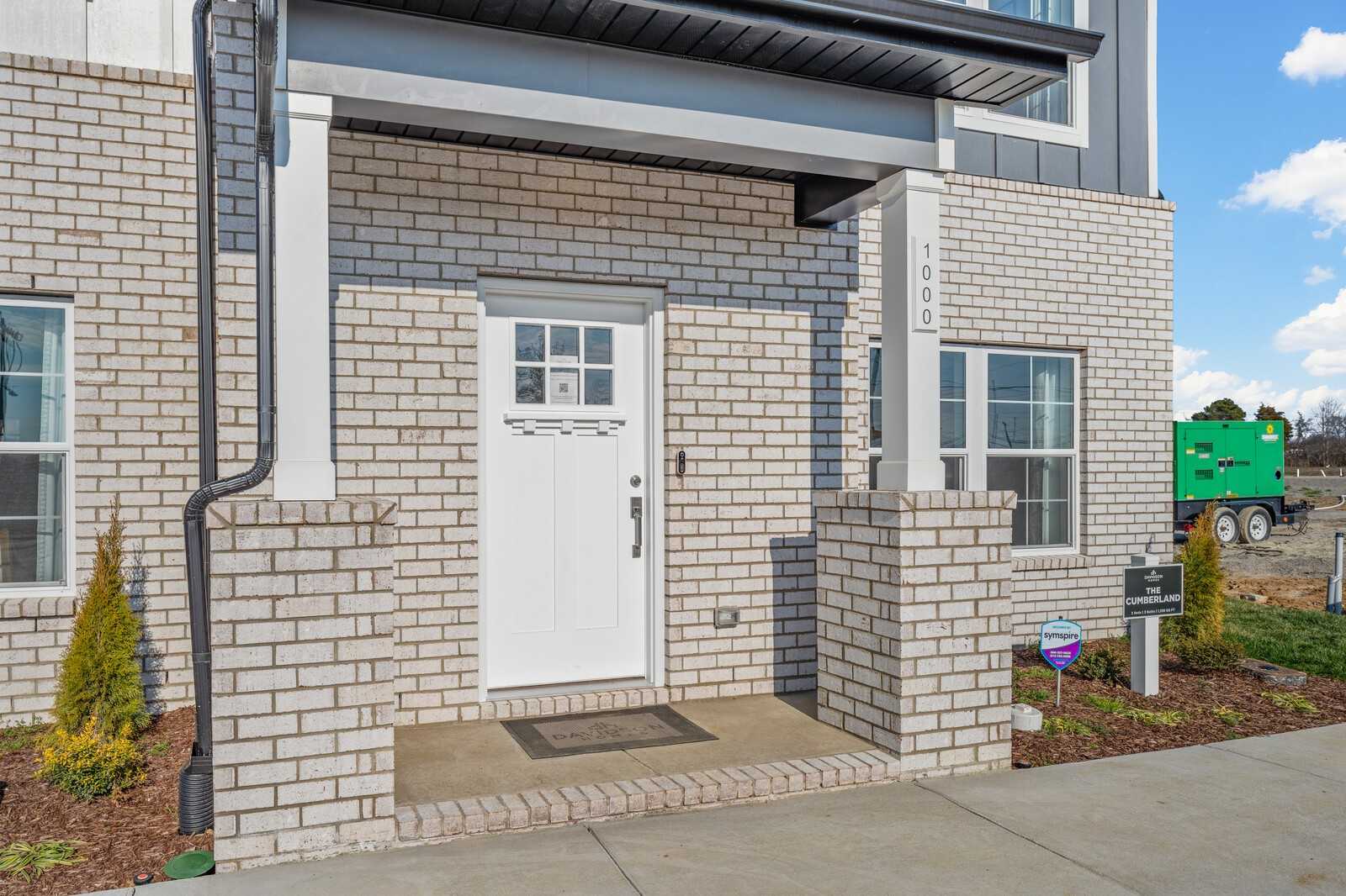 Modern brick exterior of Davidson Homes Cumberland B with covered porch, white door, and windows in The Towns at Red River, Gallatin, Tennessee