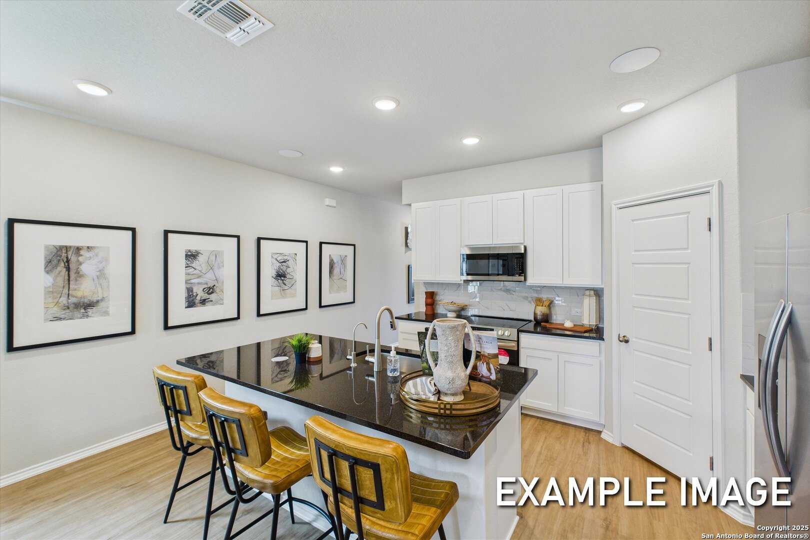 Modern kitchen with white cabinets, black granite island, stainless appliances in Davidson Homes The Sabine C, San Antonio