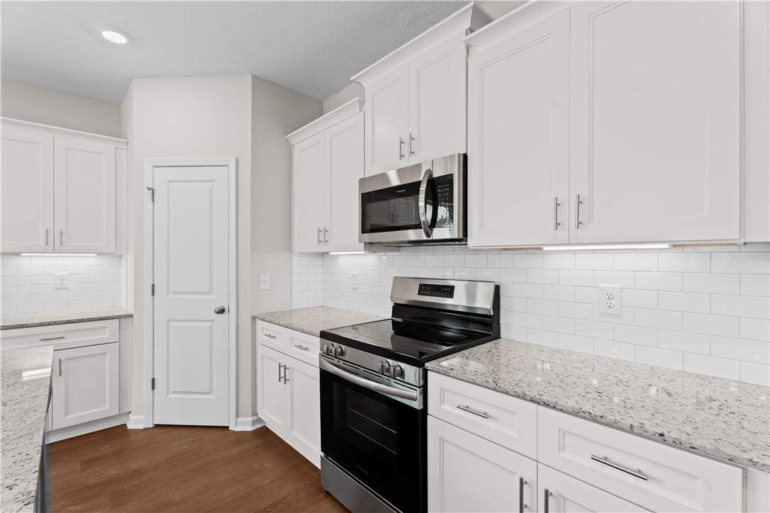 Bright modern kitchen with white shaker cabinets, speckled granite counters, stainless appliances in Orion home, Cusseta AL