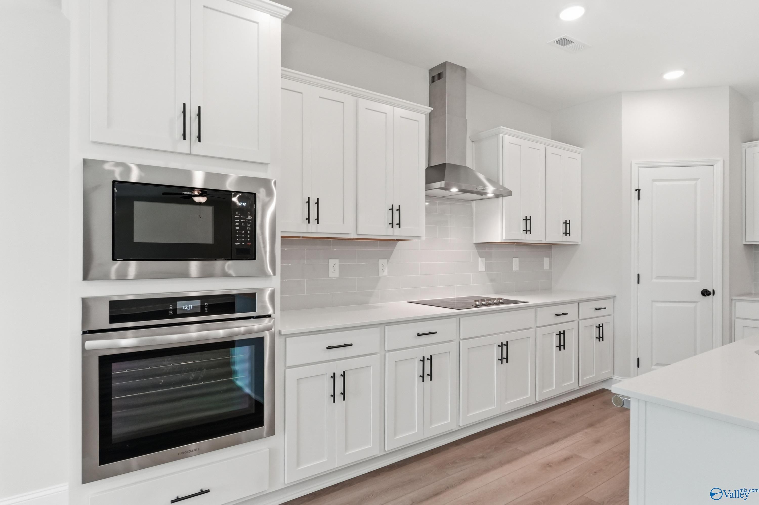 Modern white shaker kitchen with Frigidaire double oven, induction cooktop, quartz counters in Davidson Homes The Rockford B, Athens, AL