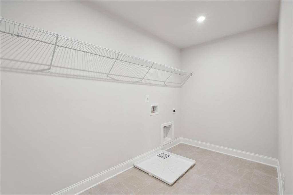 Laundry room with wire shelving, tile flooring, and washer drain pan in Davidson Homes The Hickory A, Cedar Farms, Winder, GA