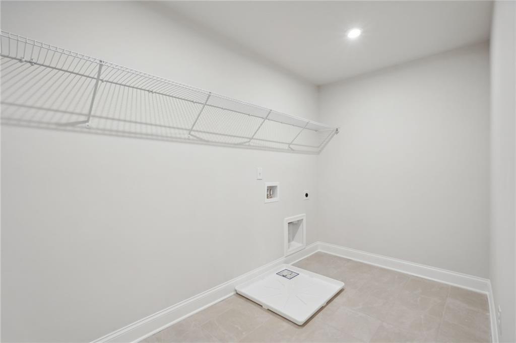 Laundry room with wire shelving, tile flooring, and washer drain pan in Davidson Homes The Hickory A, Cedar Farms, Winder, GA