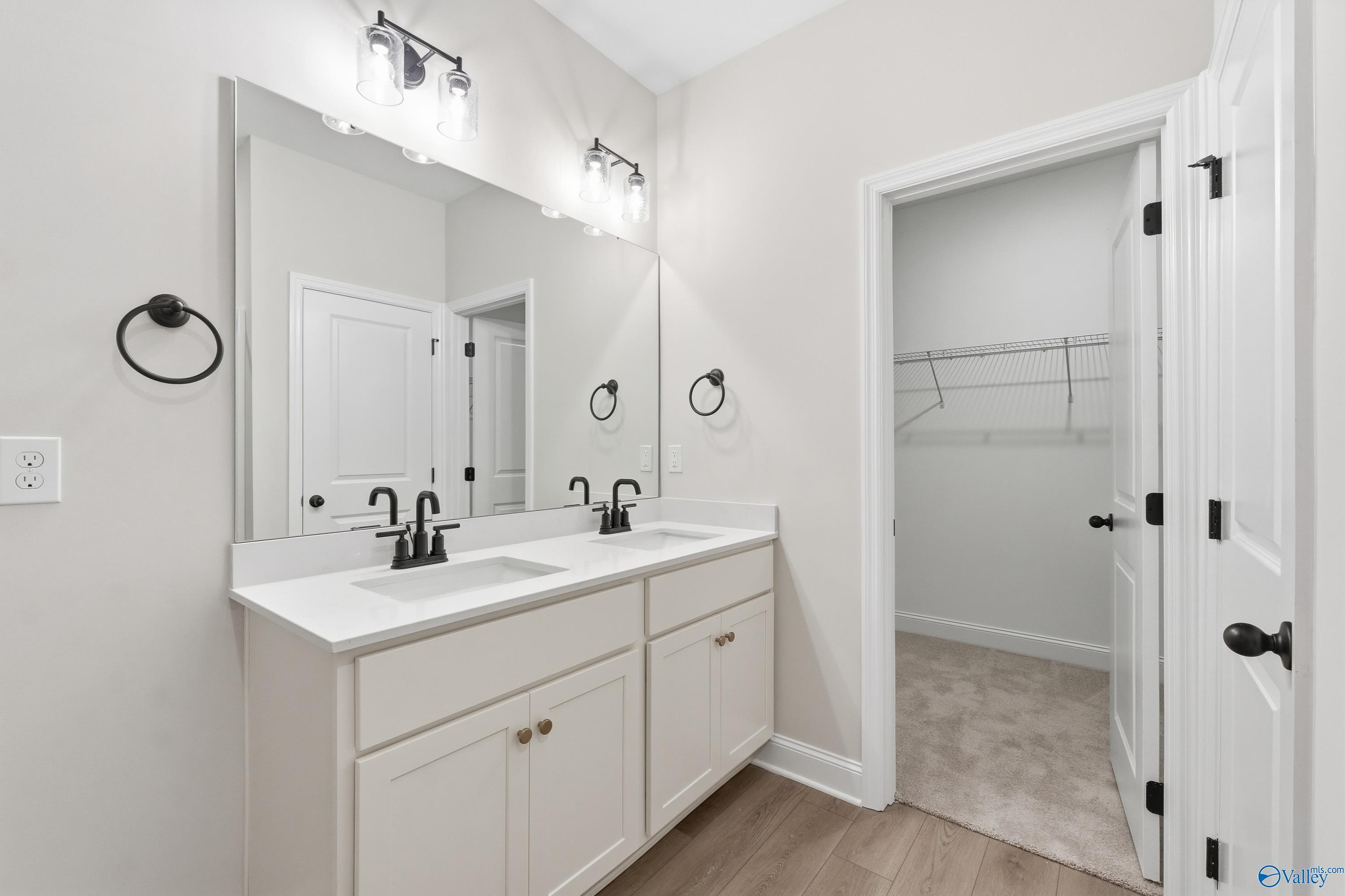 Modern master bathroom with double white quartz vanity, black faucets, sconces, and open walk-in closet in Davidson Homes The Franklin C, Meridianville, Alabama