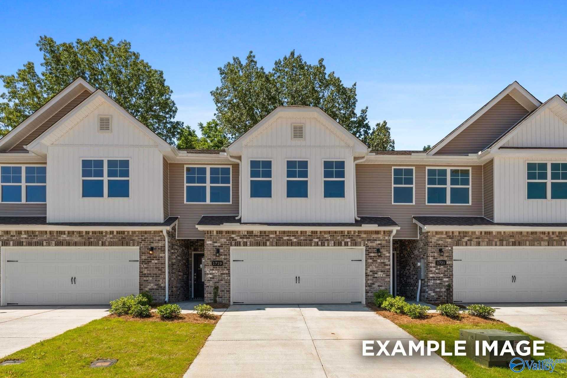 Three attached 2-story townhomes with stone facades, 2-car garages, and blue sky in Pavilion, Huntsville, Alabama by Davidson Homes