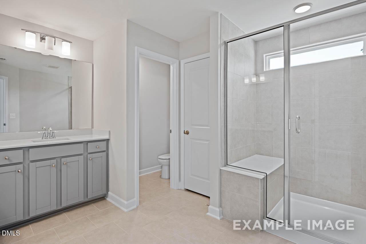 Modern bathroom with gray vanity and glass-enclosed walk-in shower in The Graham floor plan at Springvale, Fuquay-Varina.