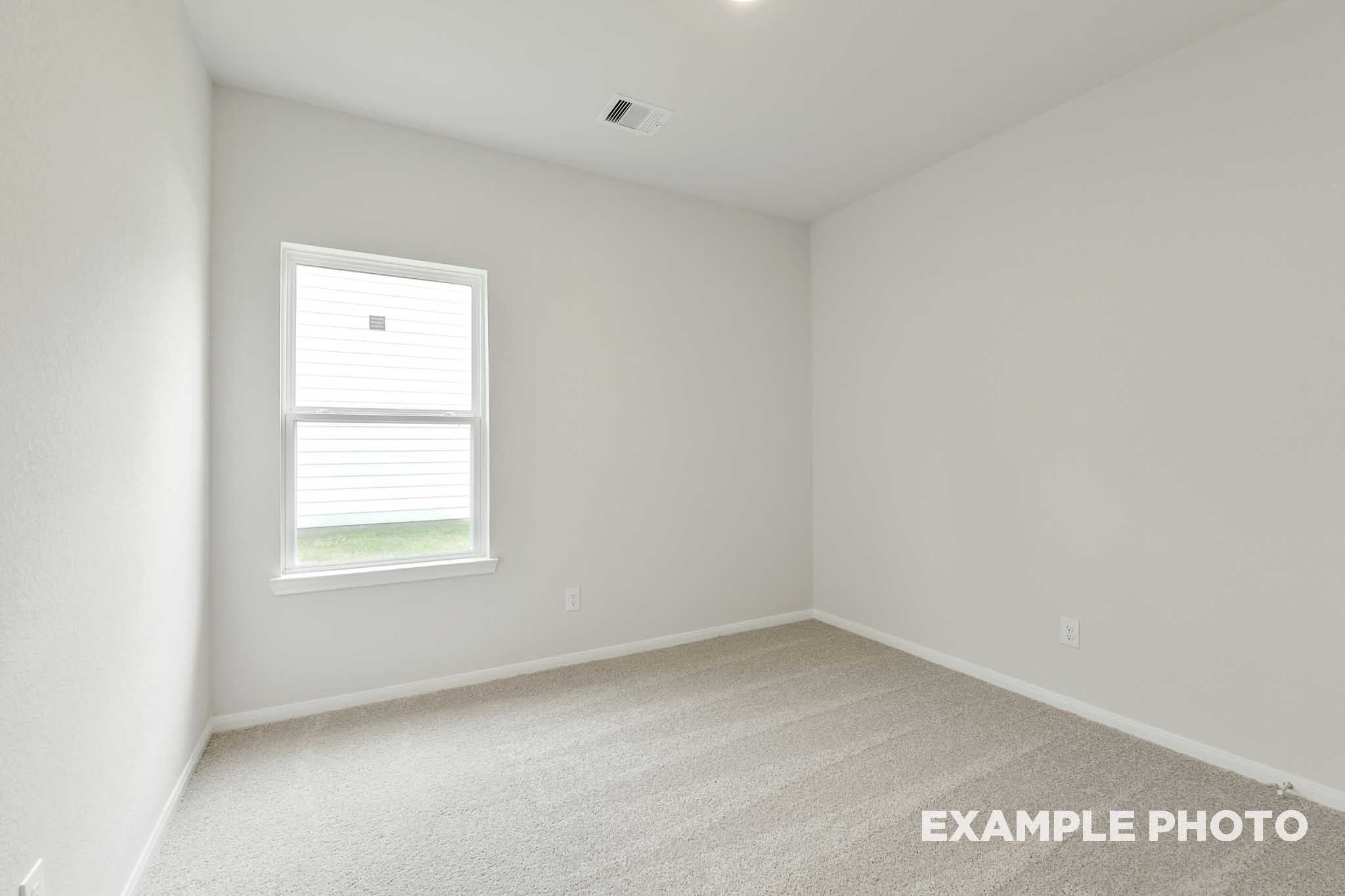 Bright, carpeted secondary bedroom in The Frio floor plan by Davidson Homes featuring neutral walls and a large window.