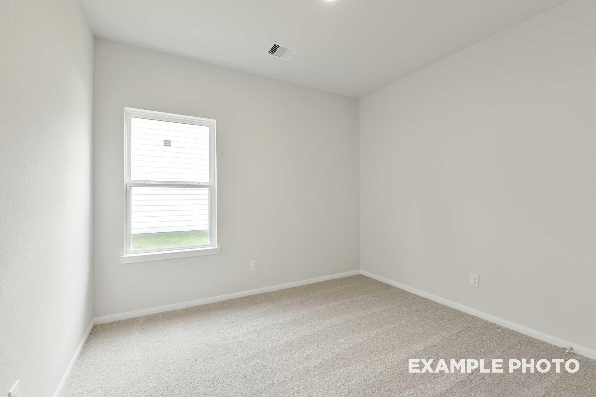 Bright, carpeted secondary bedroom in The Frio floor plan by Davidson Homes featuring neutral walls and a large window.