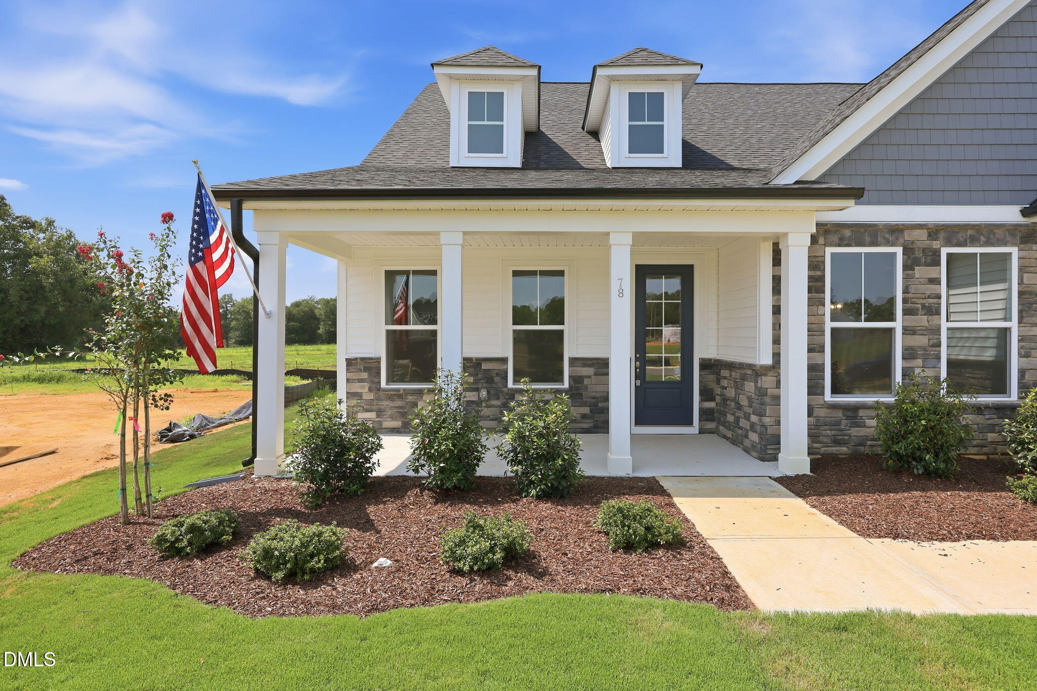 Exterior of The Magnolia B model home with stone facade and covered front porch in Retreat at North Main, Lillington, NC.