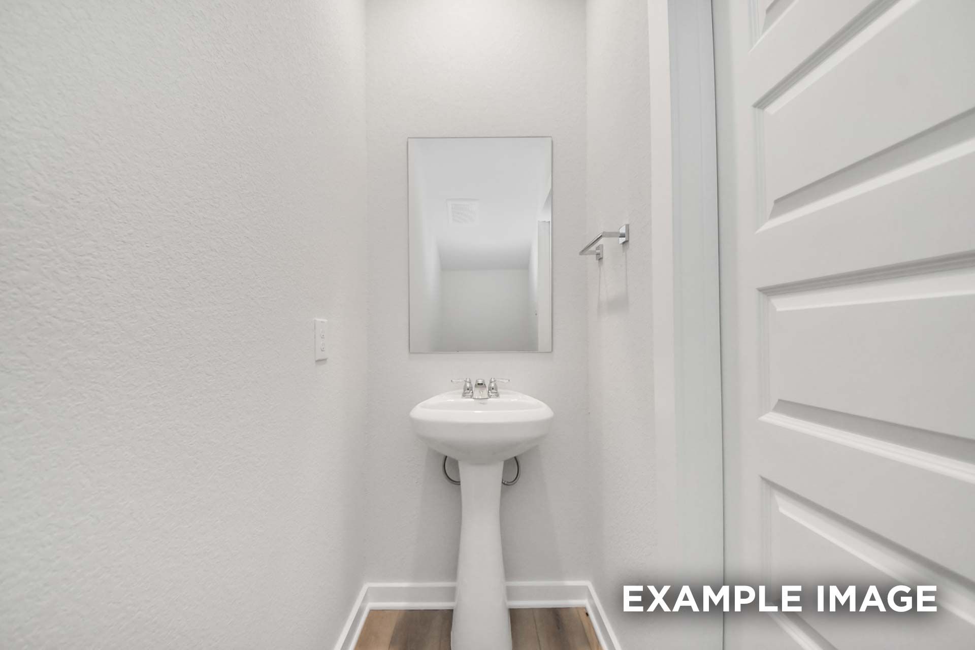 Powder room in The Blanco by Davidson Homes featuring pedestal sink, mirror, and wood-look flooring in Beasley, TX home