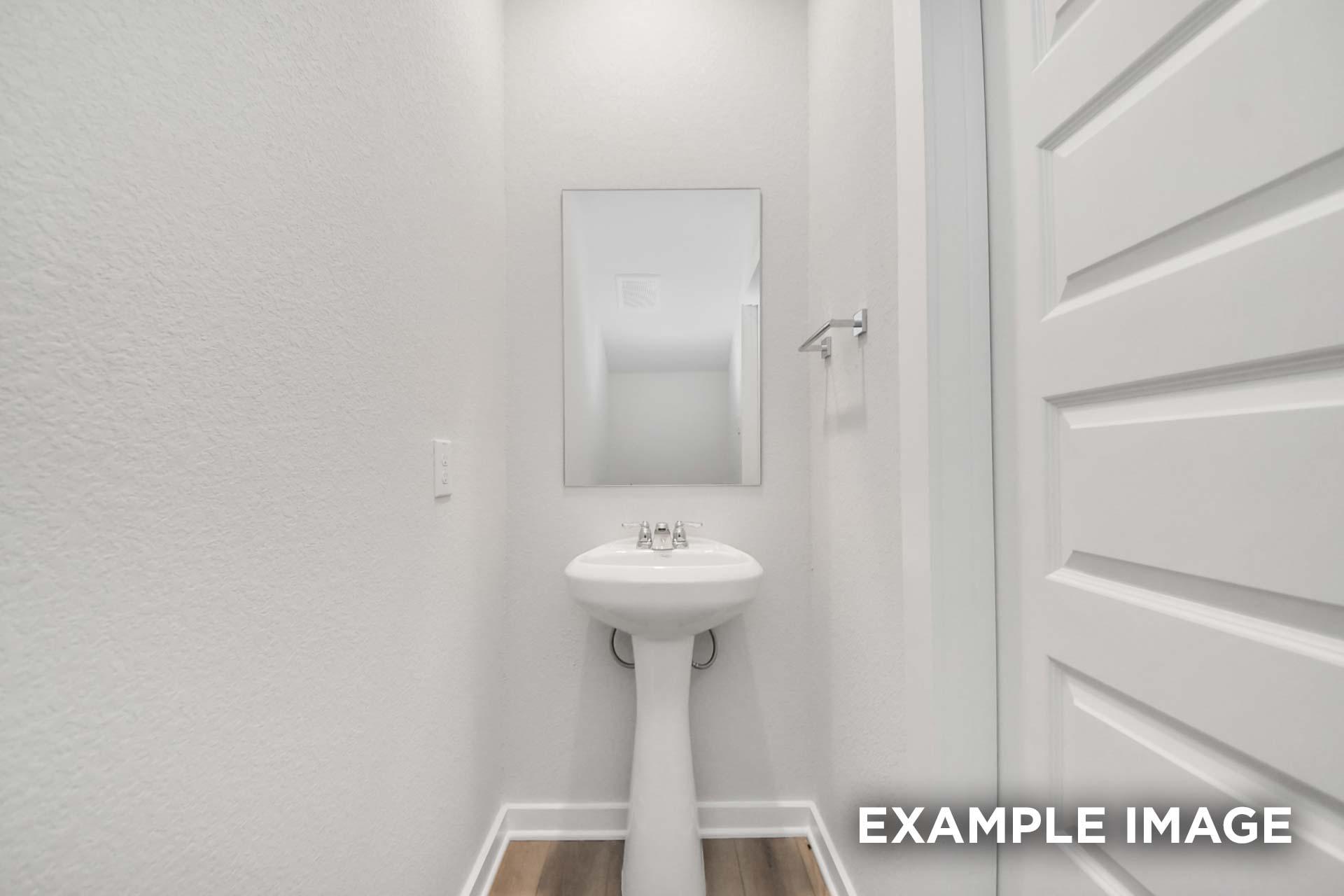 Powder room in The Blanco by Davidson Homes featuring pedestal sink, mirror, and wood-look flooring in Beasley, TX home