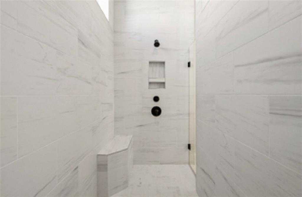 Luxurious walk-in shower with white marble tiles, glass enclosure, built-in bench, and rain showerhead in Davidson Homes Seaside A, Woodstock GA