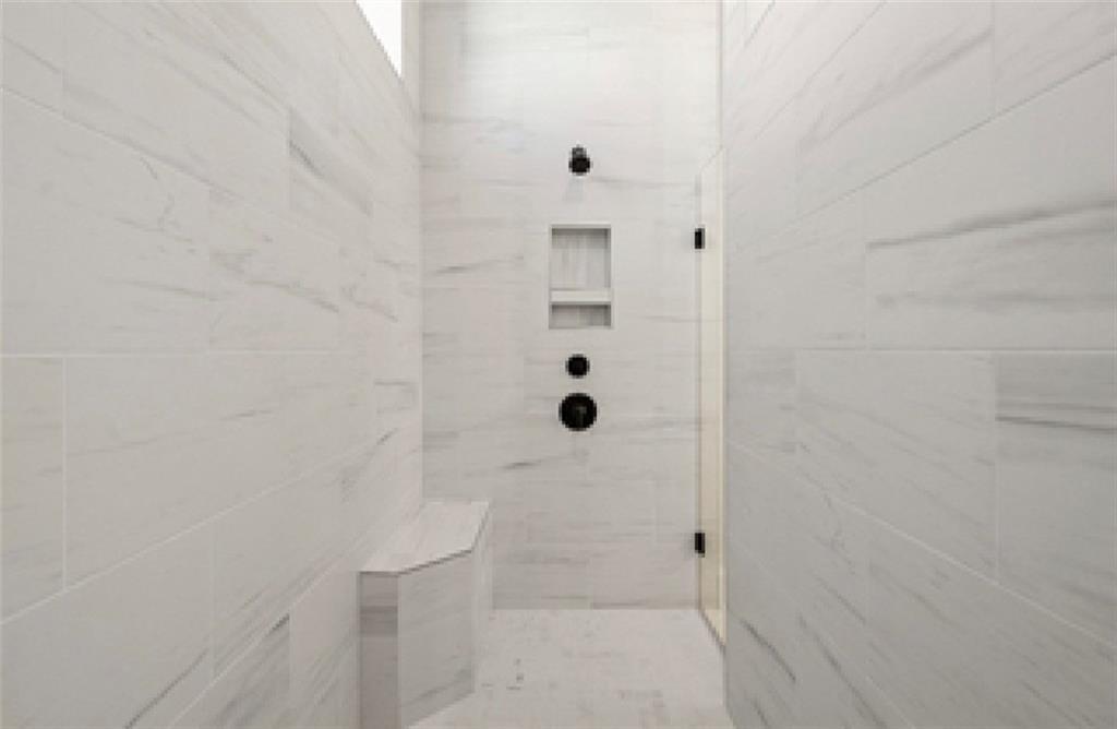 Luxurious walk-in shower with white marble tiles, glass enclosure, built-in bench, and rain showerhead in Davidson Homes Seaside A, Woodstock GA