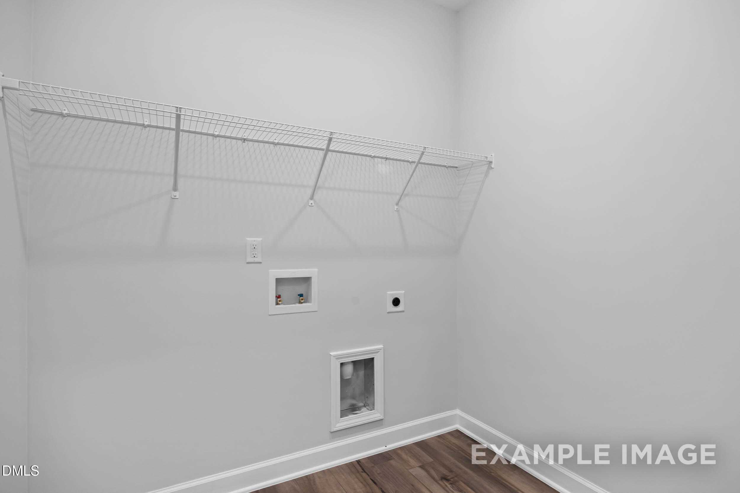 Spacious laundry room with wire shelving, washer/dryer hookups and hardwood floor in The Ash B by Davidson Homes, Lillington, NC
