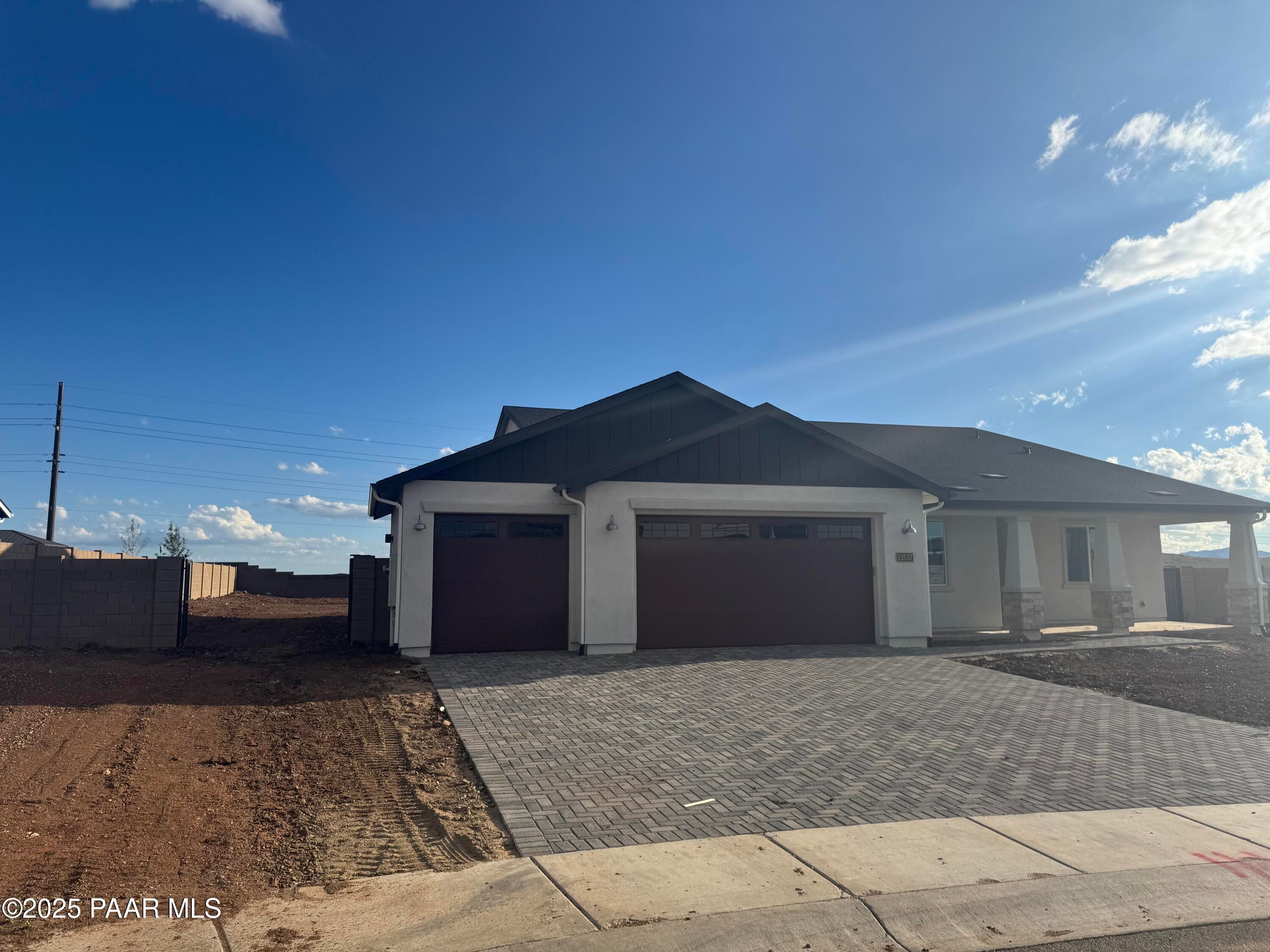Modern single-story home with dark gabled roof, white exterior, 4-car garage, and paver driveway in Morningstar, Prescott Valley, Arizona