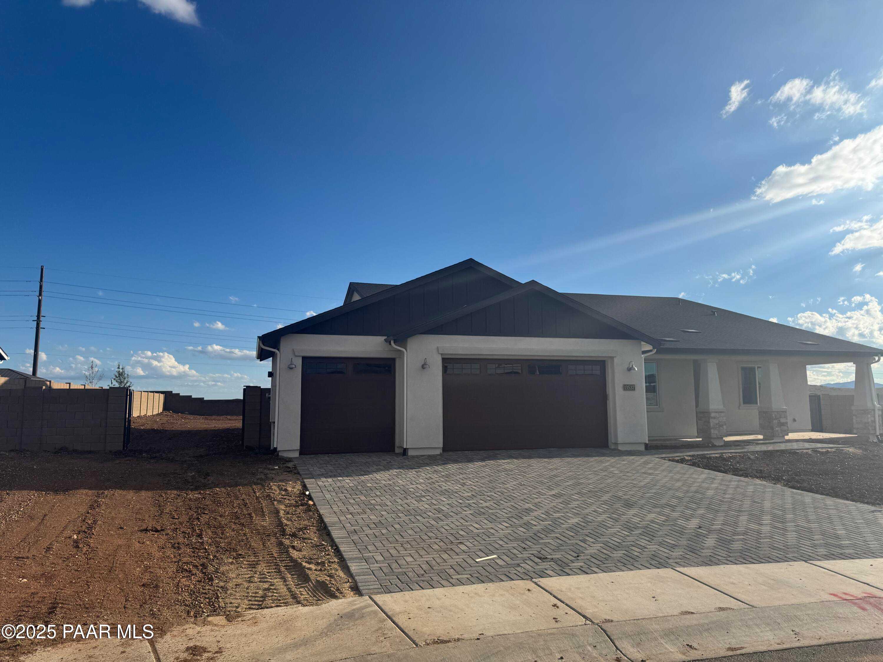 Modern single-story home with dark gabled roof, white exterior, 4-car garage, and paver driveway in Morningstar, Prescott Valley, Arizona